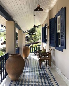 a blue and white checkered tile covered porch with potted plants on the side