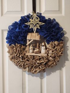 a nativity wreath hanging on a door with blue ruffles and a star