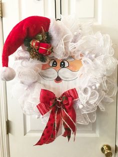 a door hanger with a santa claus face on it's side and bells hanging from the front