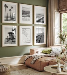 a living room with green walls and pictures on the wall above the couch, along with vases filled with flowers