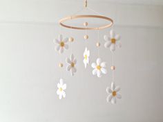 a white and yellow mobile with flowers hanging from it's sides on a wall