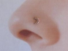 a close up of a nose with a small crescent piercing on it's side