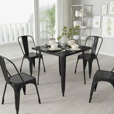 black dining room furniture set with glass table and four chairs in front of large window