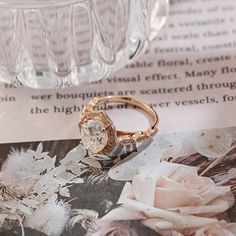 a close up of a ring on top of an open book with flowers in the background