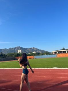 a woman in a bathing suit is playing frisbee on a tennis court with mountains in the background