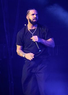 a man standing on stage with a microphone in his hand and wearing a black t - shirt