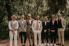 a group of men standing next to each other in front of trees wearing suits and ties