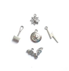 several charms are arranged on a white surface, including one with a bat and the other with a spiderweave