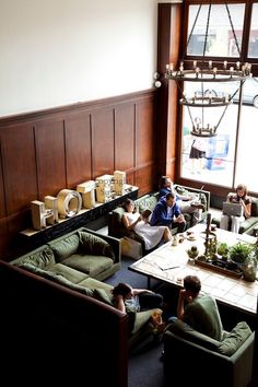 people sitting at tables in a restaurant with green couches and wood paneled walls