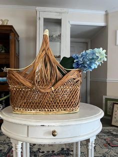 a wicker basket sitting on top of a white table next to a blue flower