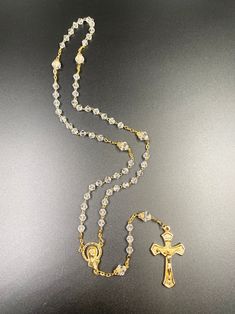 "Crystal bead and gold plated rosary prayer necklace. This reverent gold plated metal crucifix, link and pendant makes for an unforgettable gift. With clear diamond-esque beads and gold plated links this beautiful rosary measures approximately 18\" with an opening of about 11.5\". The miraculous pendant stands around 1.5\" and this lovely rosary piece weighs 20 grams. Rosario hecho a mano de crystal y metal en bano de oro." Gold Cross Crystal Necklace, Gold Cross Necklace With Crystal, Gold Crystal Cross Necklace, Gold Spiritual Jewelry With Rhinestones, Gold Cross Necklace With Rhinestones, Gold Rhinestone Cross Necklace, Spiritual Gold Rosary With 8mm Beads, Gold Necklaces With 8mm Beads For Spiritual Style, Gold Rhinestone Round Bead Necklaces