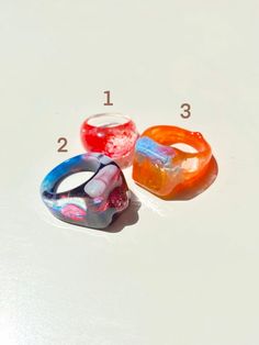 "Colorful and shiny statement rings. Each ring is one of a kind (they have different sizes). You can choose to purchase only one ring, or the three rings in the listing (Prices vary depending on the option you choose). Please select the number of the ring you want or if you would like to take all of them please click the option \"All three rings\". You will receive the exact ring/rings shown in the pictures. Ring 1 Diameter: 17 mm Ring 2 Diameter: 19 mm Ring 3 Diameter: 19 mm" Unique Clear Resin Ring, Unique Clear Resin Rings, Trendy Multicolor Resin Rings, Clear Resin Rings, Trendy Resin Ring Jewelry, Unique Multicolor Resin Ring, Trendy Resin Ring, Handmade Multicolor Resin Rings, Trendy Multicolor Plastic Rings