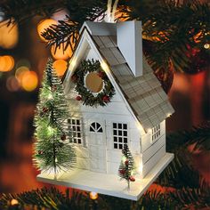 a white house ornament hanging from a christmas tree with lights and decorations on it