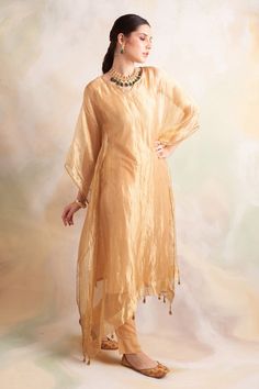 Gold tissue kaftan style kurta with lace trims and tassel hem. Comes with soft modal gold pant.
Component: 2
Pattern: Solid
Neckline: V-Neck
Sleeve Type: Batwing
Fabric: Kurta: Tissue, Pant: Soft Modal
Color: Gold
Other Details: 
Tassel hem
Lace trims
Side slits
Note: Inner worn by the model is not for sale
Occasion: Mehendi and Haldi - Aza Fashions Anarkali Kurta With Tassels For Wedding, Anarkali Kurta With Back Tassel Tie-up For Navratri, Anarkali Wedding Kurta With Tassels, Anarkali Kurta For Navratri With Back Tassel Tie-up, Navratri Anarkali Kurta With Back Tassel Tie-up, Festival Straight Kurta With Back Tassel Tie-up, Festive Kurta With Back Tassel Tie-up For Navratri, Traditional Drape Kurta With Back Tassel Tie-up For Festivals, Traditional Kurta With Back Tassel Tie-up For Festivals