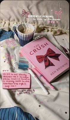 a pink book with a red bow on it next to a cup of coffee and pen