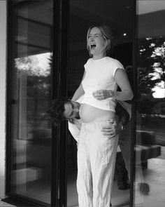 a pregnant woman standing in front of a glass door with her mouth open and tongue out