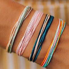 a woman's arm with five different colored bracelets on it