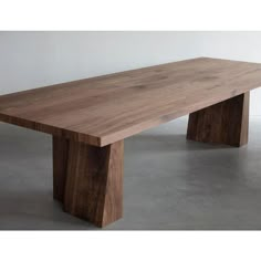 a large wooden table sitting on top of a cement floor next to a white wall