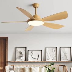 a ceiling fan in a living room with pictures on the wall behind it and a couch