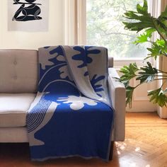 a couch with a blue and white blanket on it in front of a potted plant