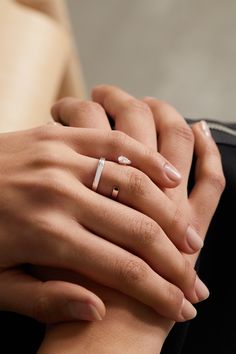 two hands holding each other while wearing rings