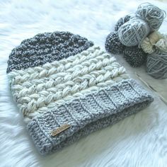 a crocheted hat sitting on top of a bed next to balls of yarn