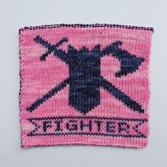 a pink and black knitted patch with two crossed swords on it, which says fighter