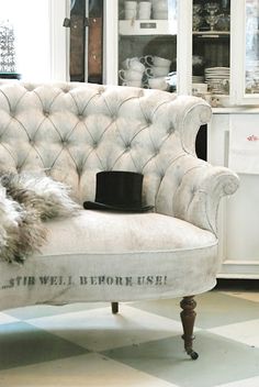 a chair with a hat on it in front of a white cabinet and shelves filled with dishes