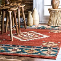 a red area rug with blue and yellow designs on it in front of a window