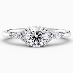 a white gold engagement ring with three stones on the band and an oval center stone