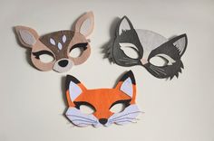 three masks with different designs on them sitting on top of a white surface, one has an animal face and the other has a fox's head