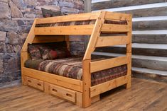 a wooden bunk bed sitting on top of a hard wood floor next to a stone wall