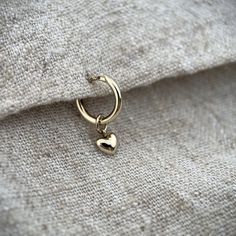 This is a delicate 1.5mm wide huggie style hoop in solid 9ct yellow gold. There are a choice of hoop sizes in the drop down menu all measurements are the distance across internally.  Hanging below the hoop is a very cute little puffy gold heart made in 9ct gold. The charm is available to buy alone without the hoop too, please choose in the options.  The heart is 4 x 4.5mm.  These hoops are great if you want a subtle look when worn alone and they also stack so well in a curated ear look.  If you Curated Ear, Huggie Earrings, Single Earring, Gold Heart, Jewelry Earrings Hoops, Gold Hoop, Huggies Earrings, Heart Of Gold, Charm Earrings