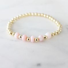 Add a pop of pink to your wrist with our Pink Opal Bracelet! This stunning bracelet features a beautiful pink opal stone, known for its calming and soothing properties.  A stone known as a love stone with a deep connection to the Heart Chakra. It works to heal our emotions, allowing our hearts to become open to love.   * 14K Gold Filled Beads   * Pink Opal Stones   * Stretch Bracelet   * Nickle and Lead Free Pink Opal Jewelry For Gift, Elegant Pink Stackable Stretch Bracelet, Adjustable Gold Jewelry With Pink Opal, Adjustable Pink Opal Gold Jewelry, Pink Opal Bracelet Jewelry, Adjustable Gold Pink Opal Jewelry, Pink Stackable Bracelets For Healing, Dainty Pink Bracelet With Natural Stones, Dainty Pink Natural Stone Bracelet