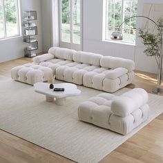 a large white couch sitting on top of a wooden floor next to a table and chair