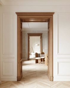 an open door leading to a living room with white walls and parquet flooring