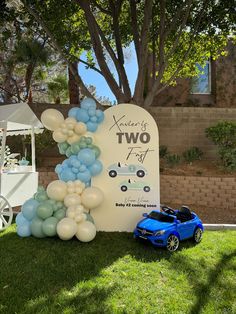 a blue toy car is parked next to a sign that says two feet and balloons