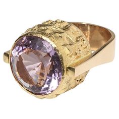 This 18 karat gold ring from 1969 is crowned with a striking amethyst, exuding classic cocktail ring grandeur. The stone's purple hue is captivating, set within a beautifully patterned mount that catches the light. The band's form is solid, with an embellished setting that echoes Egyptian symbols, offering a distinct texture that contrasts elegantly with the amethyst's smoothness. This piece is a statement of 1960s luxury, perfect for adding a touch of sophistication to any outfit. Consider wear Medieval Wedding Ring, Rings Purple, Gothic Wedding Rings, Amethyst Cocktail Ring, Gothic Engagement Ring, Medieval Rings, Victorian Engagement Rings, Gothic Ring, Crown Gold