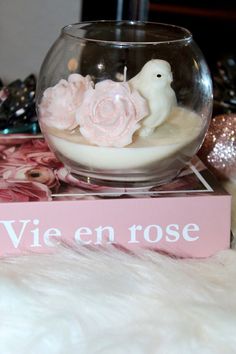 a glass bowl filled with water and flowers on top of a pink sign that says vie en rose