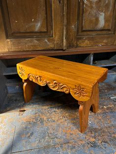 a wooden bench sitting on top of a stone floor next to a brown cabinet and door