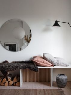 a white room with a mirror and some pillows on the floor next to a bench