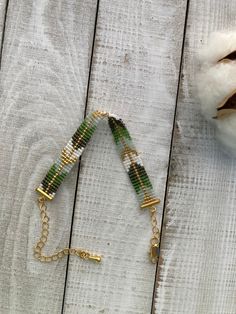 a green beaded bracelet sitting on top of a wooden table