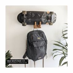 a skateboard hanging on the wall with a back pack attached to it's side