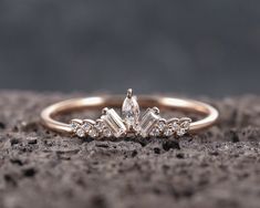 a gold ring with three stones on it sitting on top of a stone surface in front of the camera