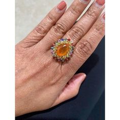 This is part of Chairish’s Fine Jewelry assortment.  7.11 Carat Pear Cut Natural Fire Opal Sapphire Yellow Gold Cocktail Ring  Item Specs:  Natural Orange Fire Opal (Pear Cut) = 3.27 Carats 18 Natural Yellow Sapphires (Round Cut) = 1.32 Carats 20 Natural Multi-Color Sapphires (Round Cut) = 2.52 Carats Total Carat Weight = 7.11 Carats 14KY Gold = 7.3 Grams Ring Size = 7 (Complimentary ring sizing available upon request) Yellow Gold Cocktail Ring, Gold Cocktail Ring, Gold Cocktail, Yellow Sapphire, 7 11, Pear Cut, Ring Size 7, Cocktail Ring, Cocktail Rings