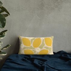 a yellow and green pillow sitting on top of a bed next to a potted plant