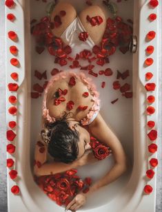 a woman laying in a bath filled with roses