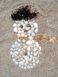 there is a snowman made out of rocks and shells on the sand with a black hair sticking out of it