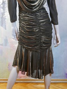 This 1980s glitter dress shimmers with gold on a black background. The stunning Austrian vintage dress has a V neckline, padded shoulders, bracelet-length sleeves, and a goddess folds yoke that drapes over the front and back to waist length The dress has a fitted waistline that gives way to a goddess pleated slimline fall to just below the hip line, where an 11-inch (27.94cm) softly ruffled panel falls to the hemline. The dress is lined in a black satin viscose fabric, and a long back zipper mak Gold Fitted Disco Dress, Metallic Fitted Lurex Dress, Fitted Metallic Lurex Dress, Gold Disco Evening Dress, Gold Black Dress, Silver Evening Dress, Girls Special Occasion Dresses, Gold And Black Dress, A Goddess