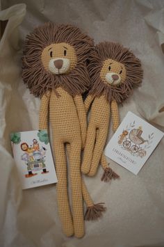 two stuffed animals sitting next to each other on top of a white cloth covered surface